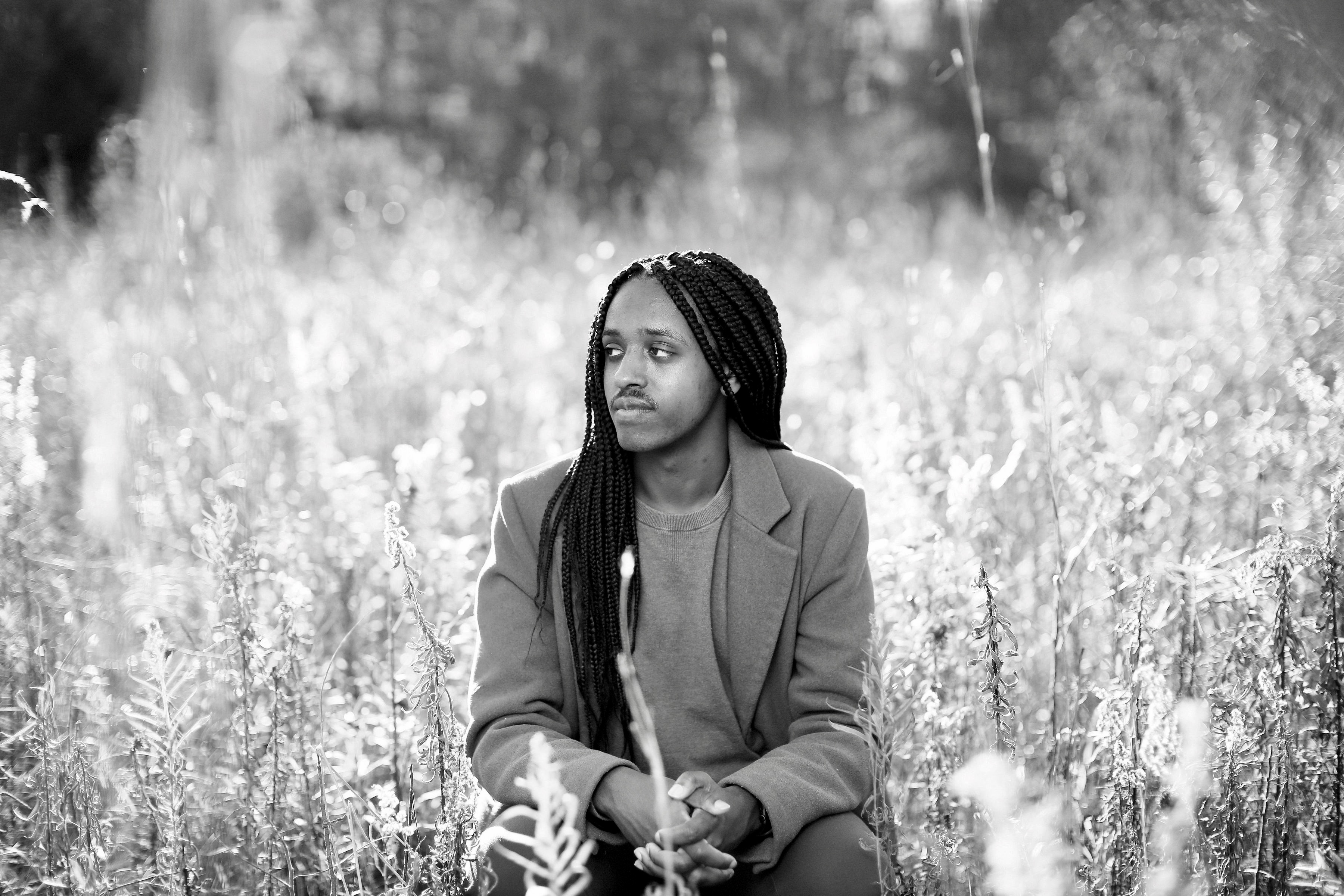 One of Hanu's senior pictures where he is sitting and smiling in a field.